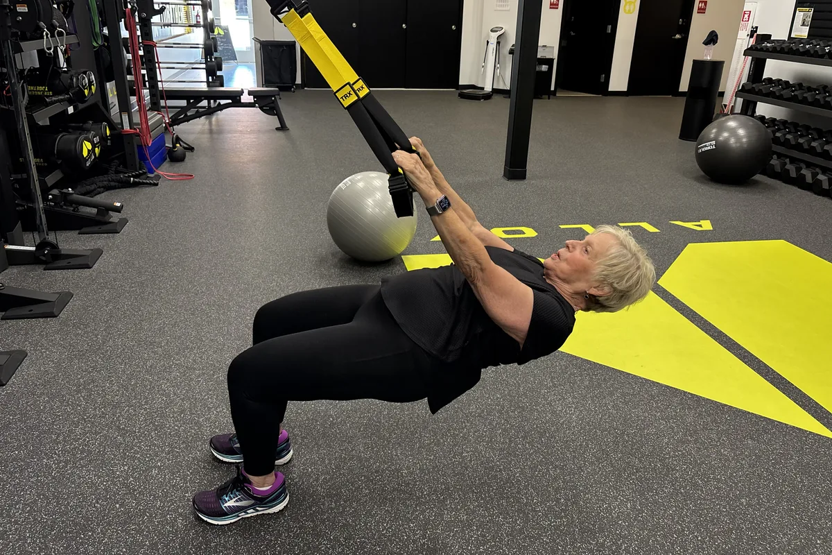 Member doing coached TRX training on the studio floor at Alloy Personal Training Cary